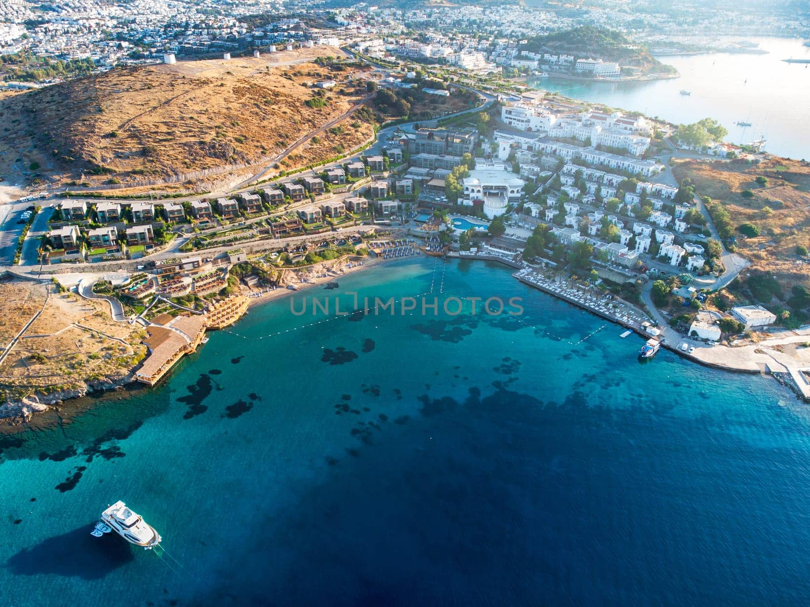 Aerial view of resort villa layout on the hill, yacht in the sea lagoon, beach surrounded by turquoise sea and hills. Beautiful beach from top. Aegean sea in Turkey. Aerial beautiful coast landscape by igor010
