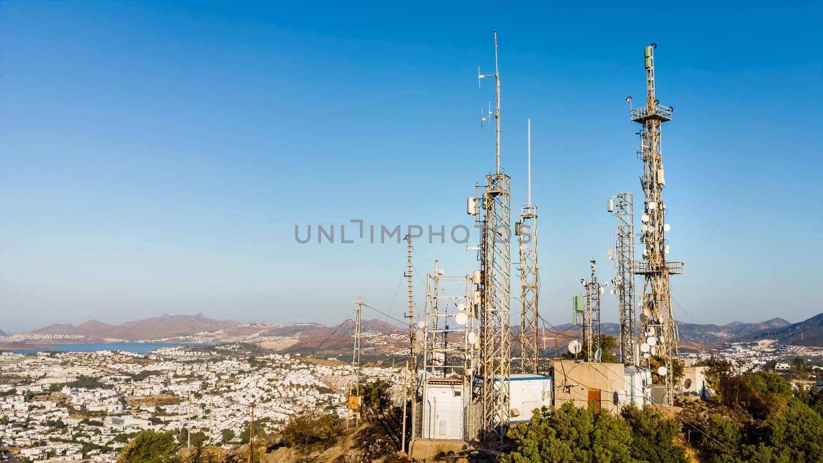 View of Telecommunication mast TV antennas at sunrise on mountain with city on background. Antenna Telephone Network Communication download photo