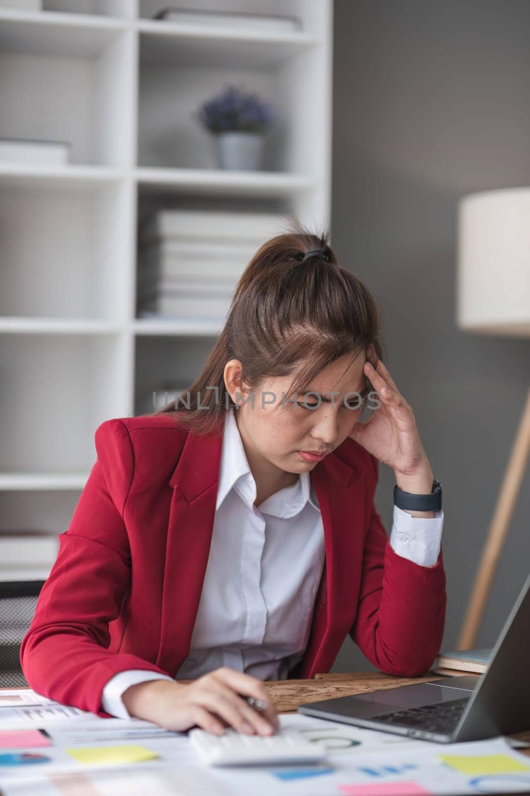 Young Asian businesswoman working on laptop computer, stressed has a headache and thinks hard from work at the office...