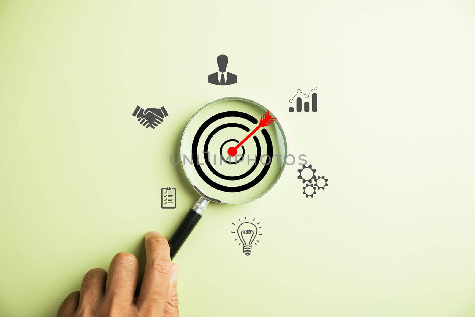 The image showcases a businessman using a magnifying glass to zoom in on the target goal icon, symbolizing the essential strategies for success in business and sustainable goals.