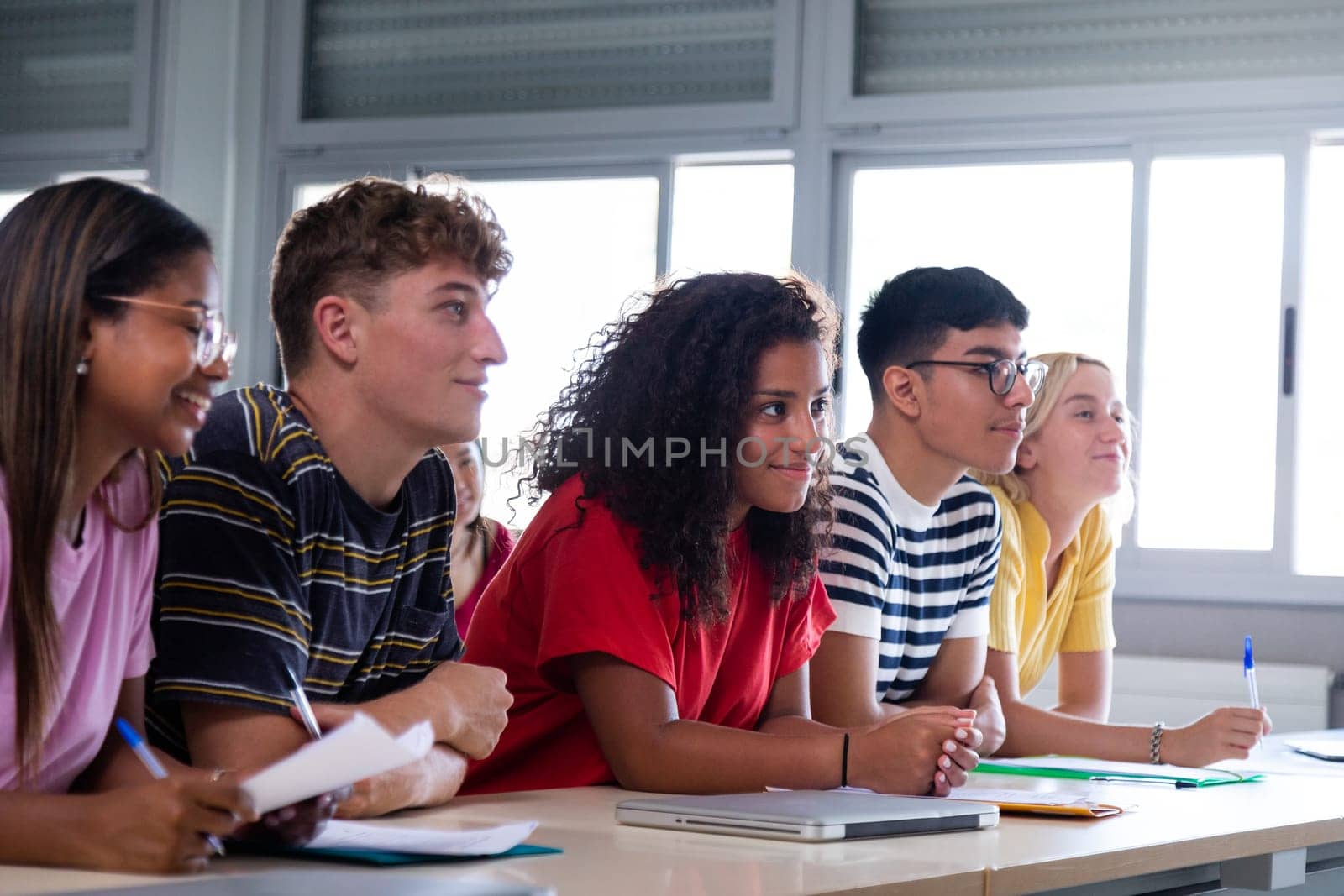Black female high school student in class with multiracial classmates. African american college student in class. by Hoverstock
