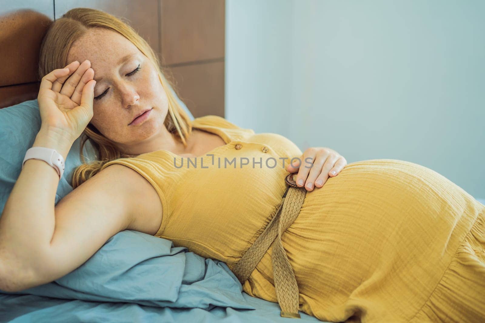 A stressed tired pregnant mother lying in bed at home. Morning sickness and nausea.