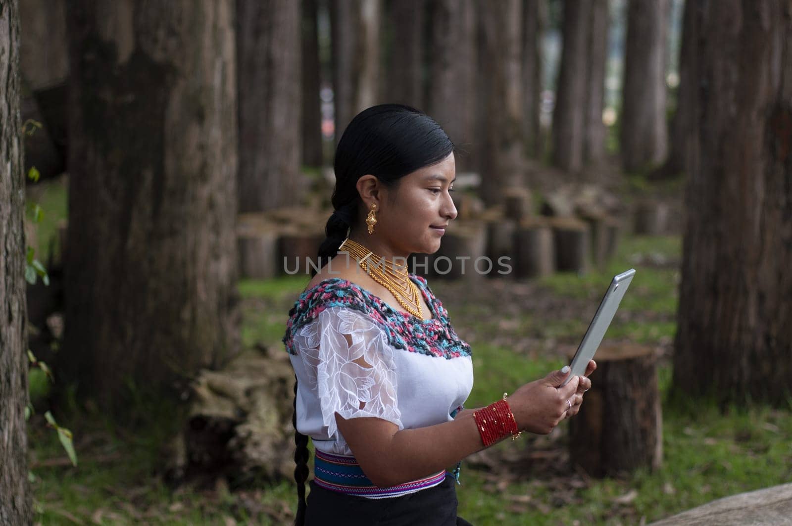 young indian woman sitting and smiling looking at a tablet while doing business online from nature. High quality photo