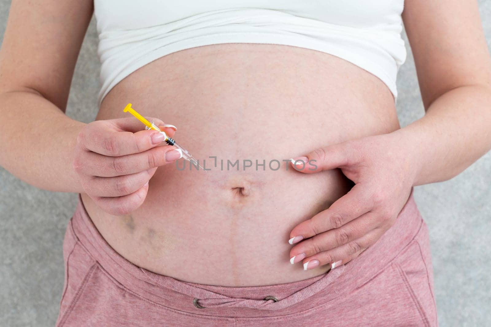 Pregnant woman making injection in stomach by Mariakray