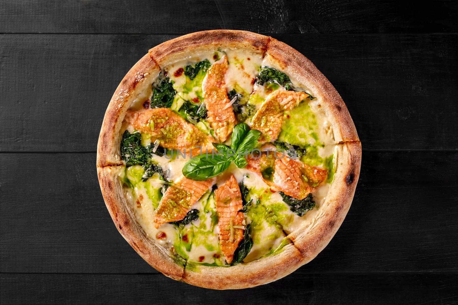 Pizza with cheese, salmon and spinach dressed with pesto and fresh basil by nazarovsergey
