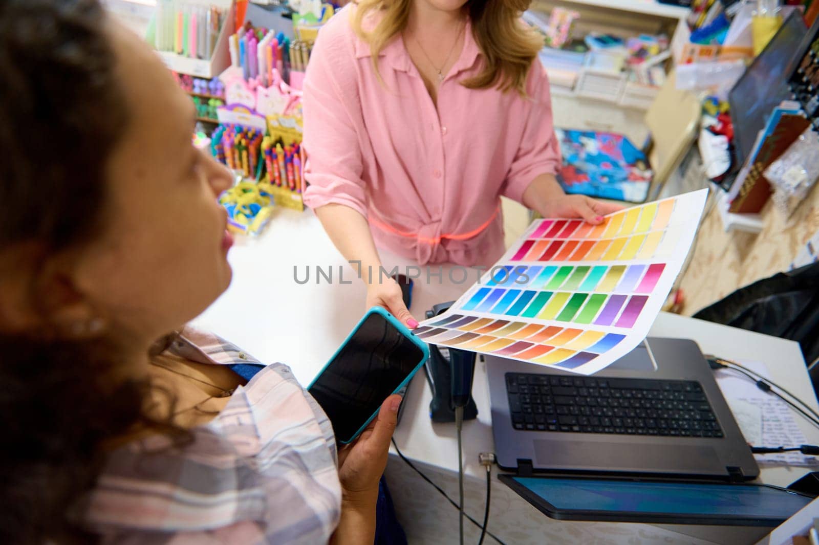 Details on palette with color samples of watercolor paints of various spectrums, in the seller hands, demonstrating it to customer shopping in a stationery store. Creativity. Hobby. Art shop. Painting