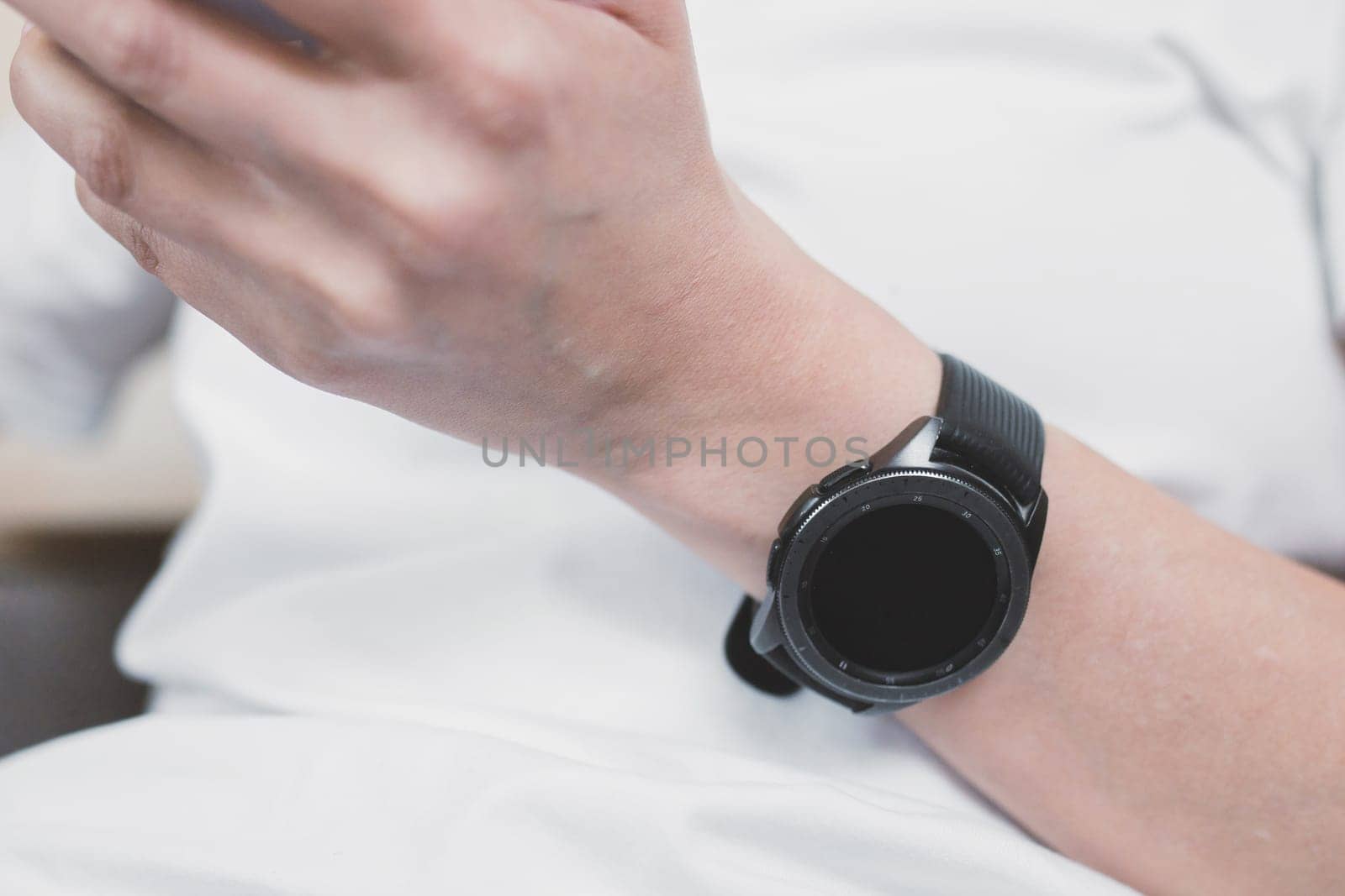Close-up on a smart watch on a female hand against the background of a white t-shirt.