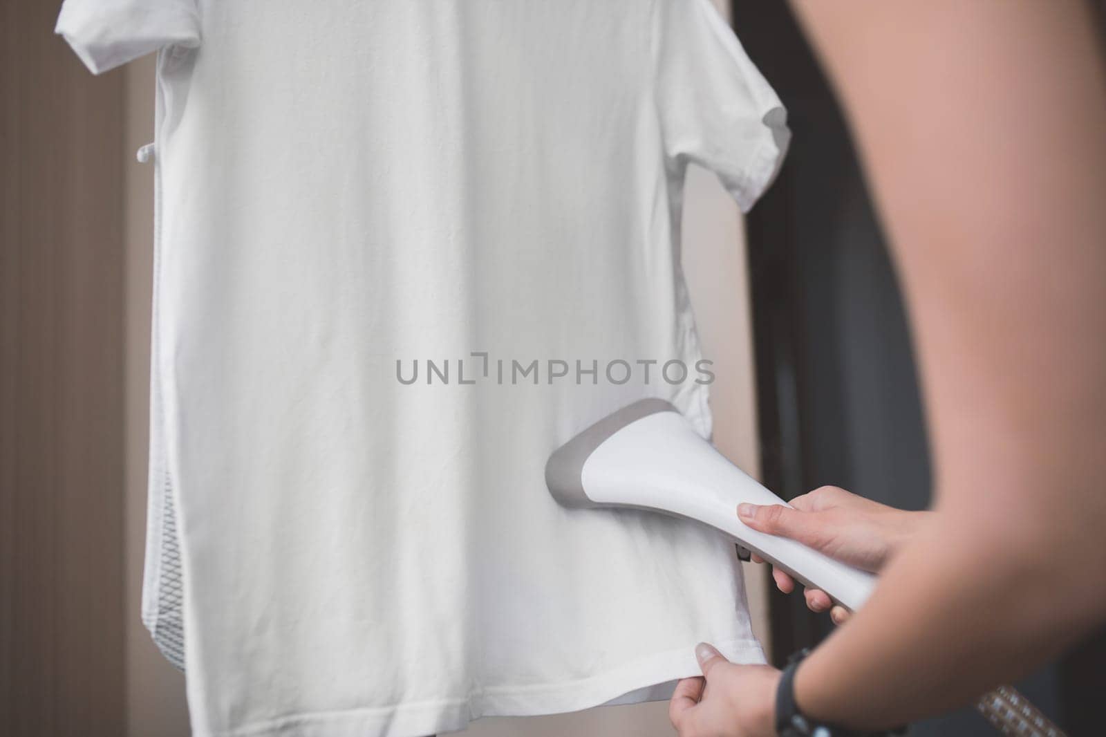 Woman steaming white t-shirt at home by Rom4ek