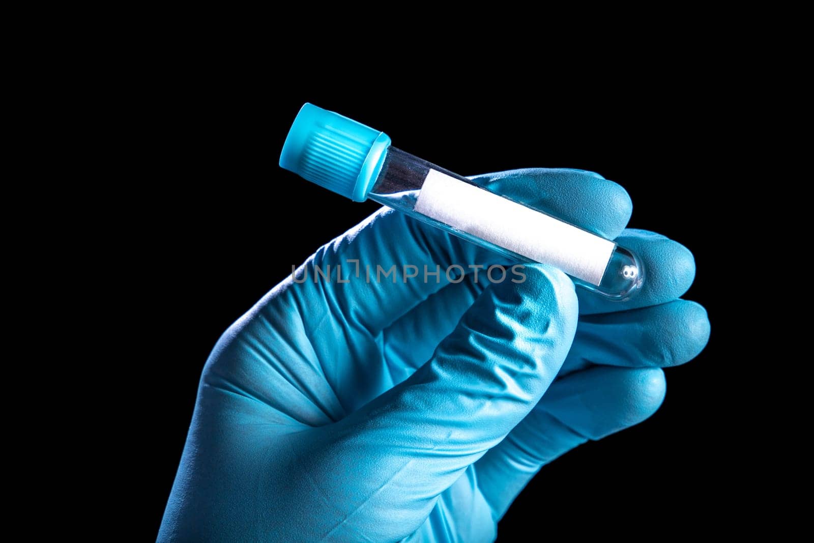 Medical test tube with copy space in hand in a medical glove on black background.