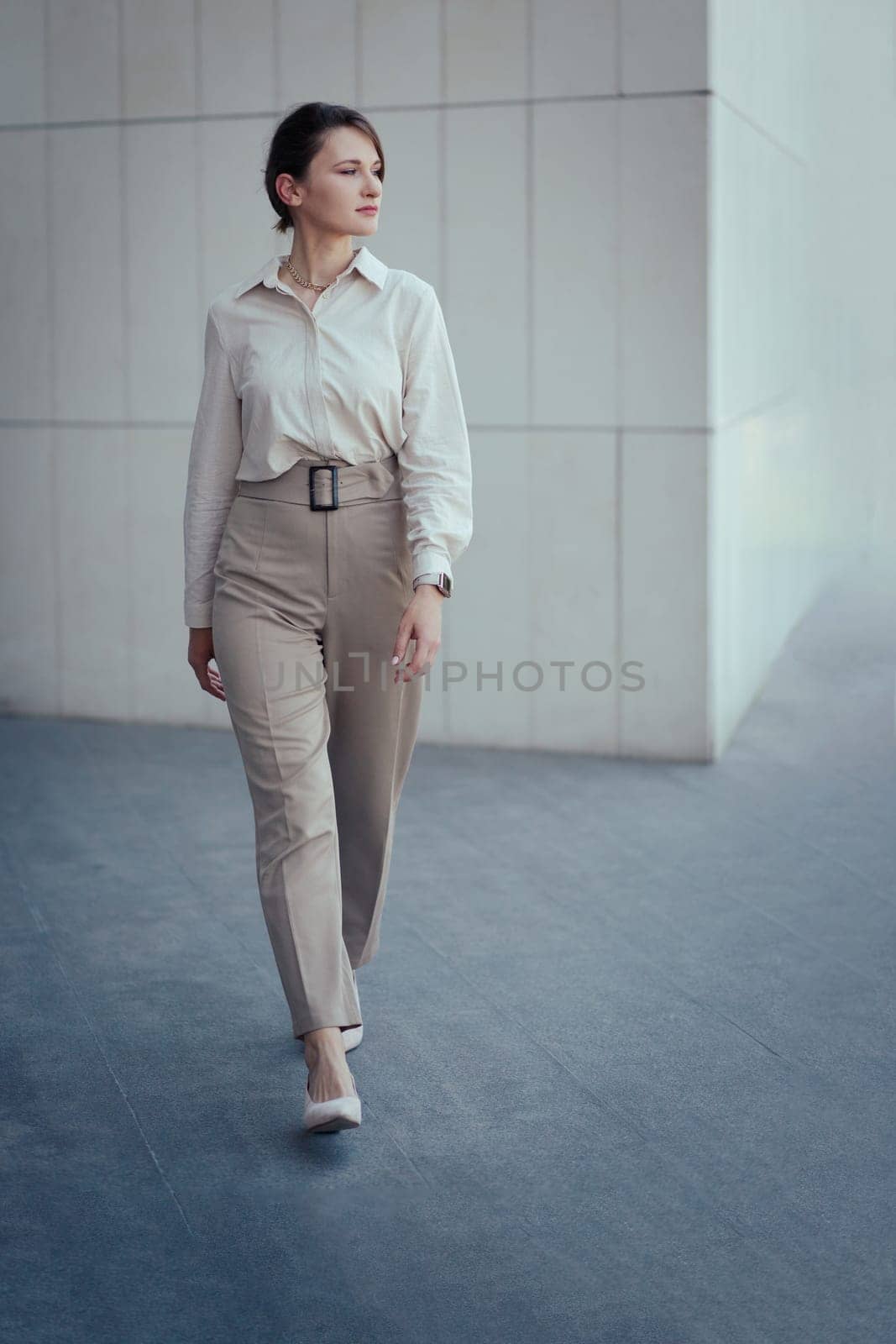 Young caucasian model woman in office or business fashion style pantsuit in brown tones, copy space, vertical.