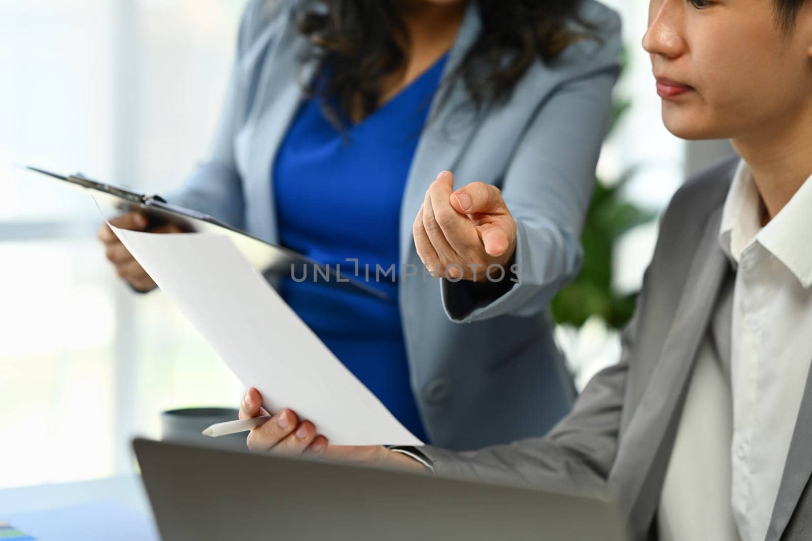 Cropped shot of male employee discussing project planning and checking financial data report with colleague.