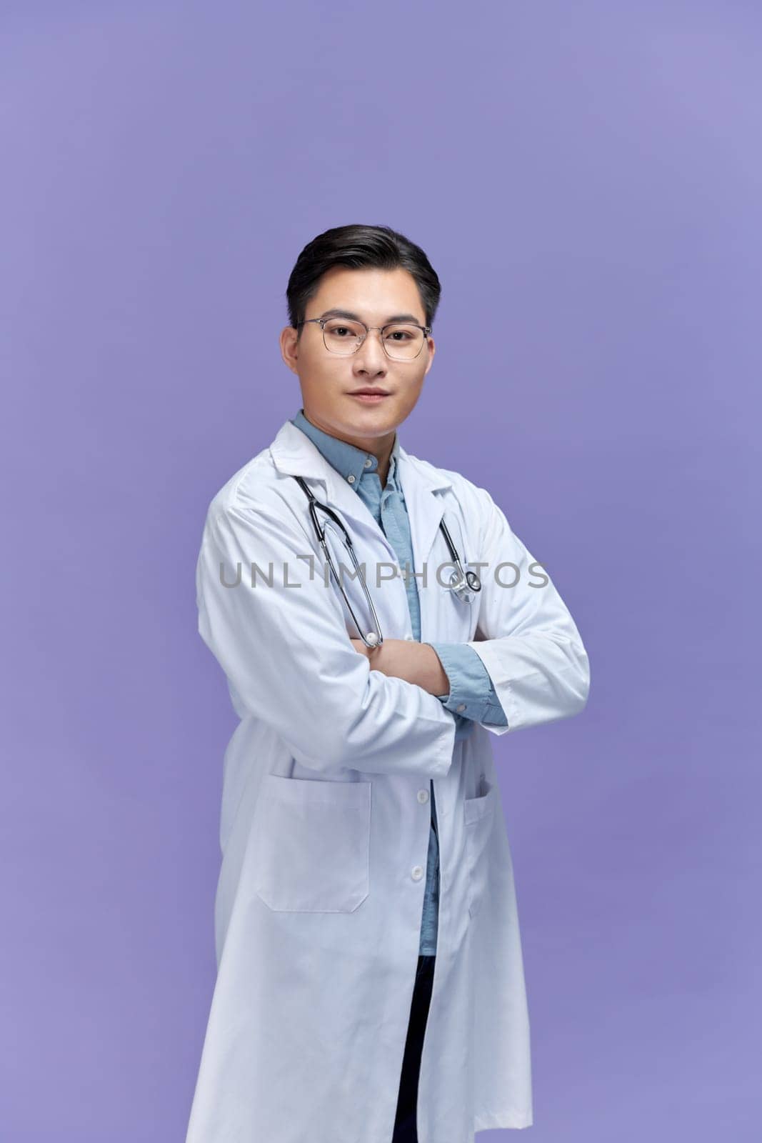 Doctor posing with arms crossed, medical staff working on purple background.