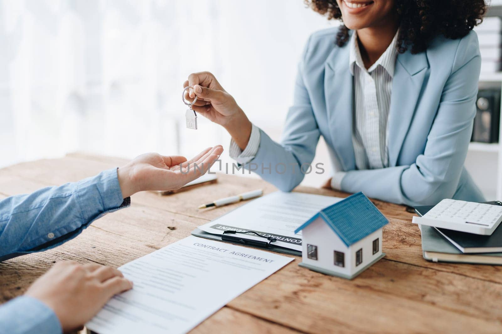 Female African american Real estate company to buy houses and land are delivering keys and houses to customers after agreeing to make a home purchase agreement and make a loan agreement. by Manastrong