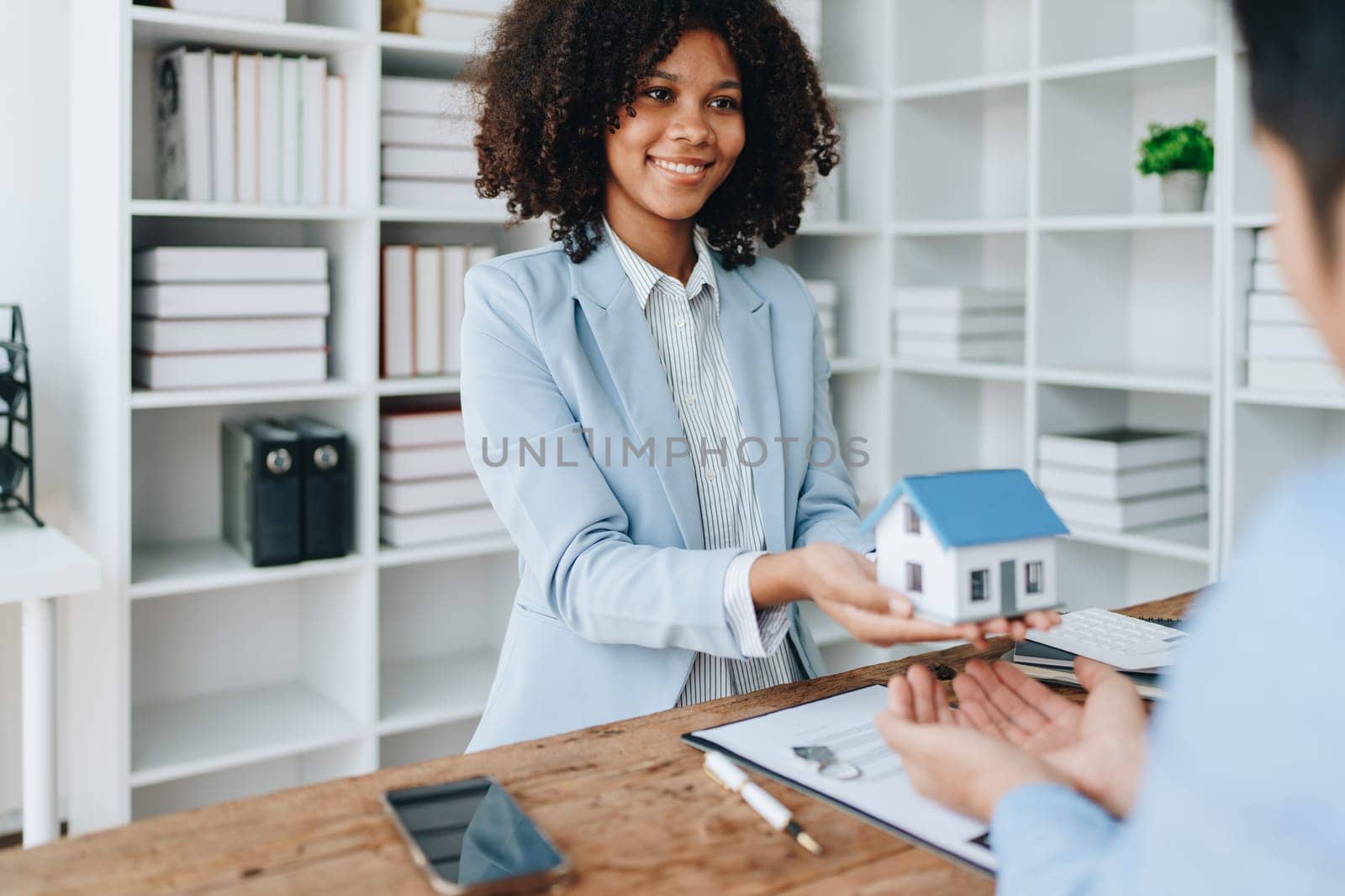 Female African american Real estate company to buy houses and land are delivering keys and houses to customers after agreeing to make a home purchase agreement and make a loan agreement. by Manastrong