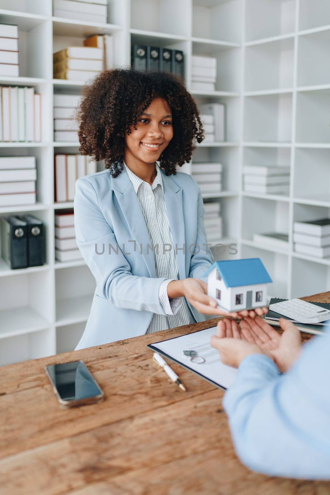 Female African american Real estate company to buy houses and land are delivering keys and houses to customers after agreeing to make a home purchase agreement and make a loan agreement. by Manastrong