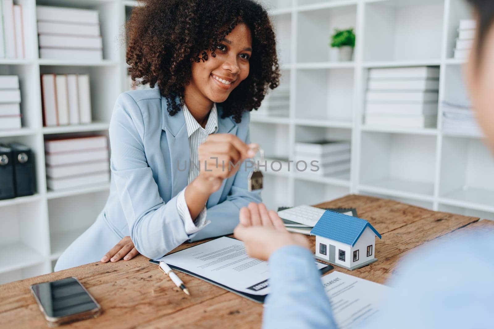 Female African american Real estate company to buy houses and land are delivering keys and houses to customers after agreeing to make a home purchase agreement and make a loan agreement. by Manastrong