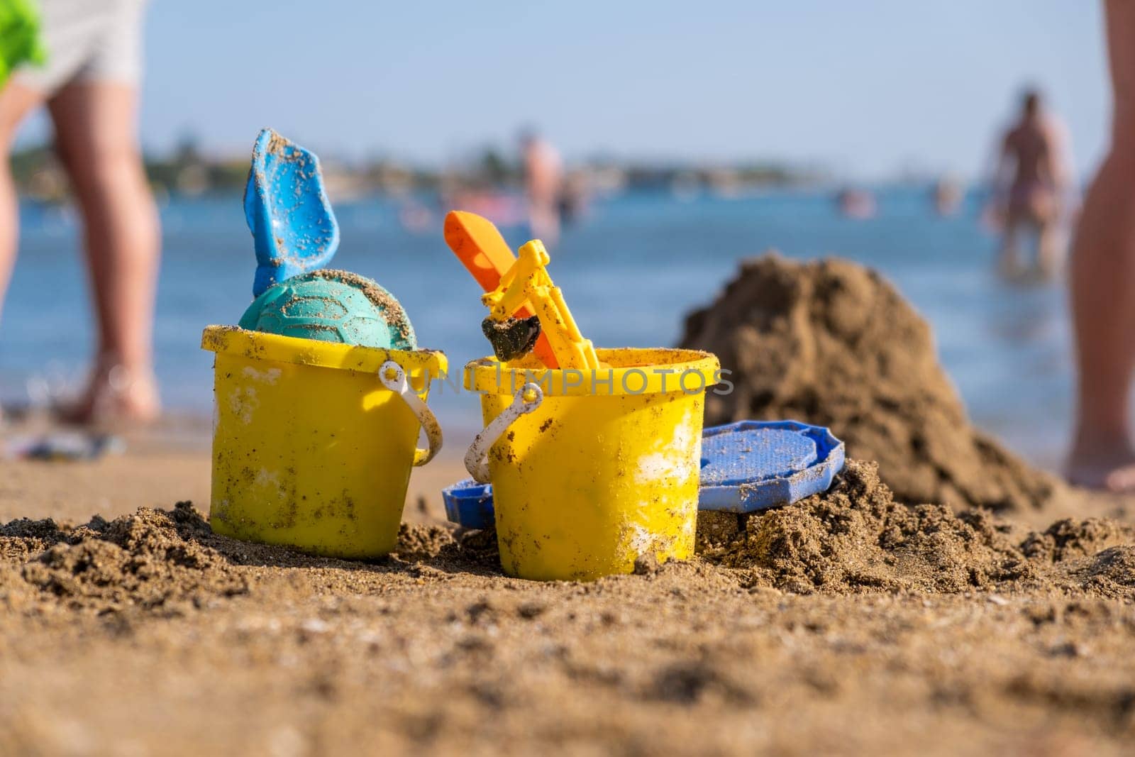 Children's beach toys buckets, spade and shovel on sand on a sunny day by AnatoliiFoto