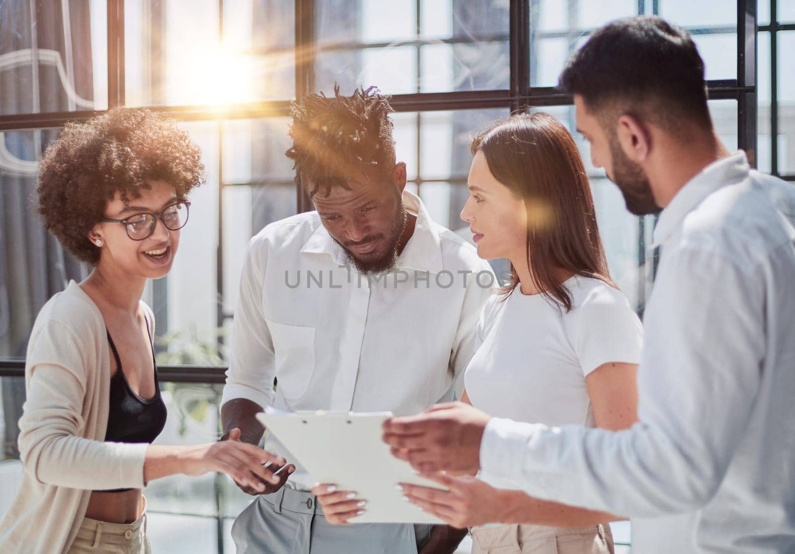 Happy young female employee discussing online project, showing computer presentation to skilled team leader in eyeglasses. Friendly diverse colleagues working in pairs on laptop, using applications.