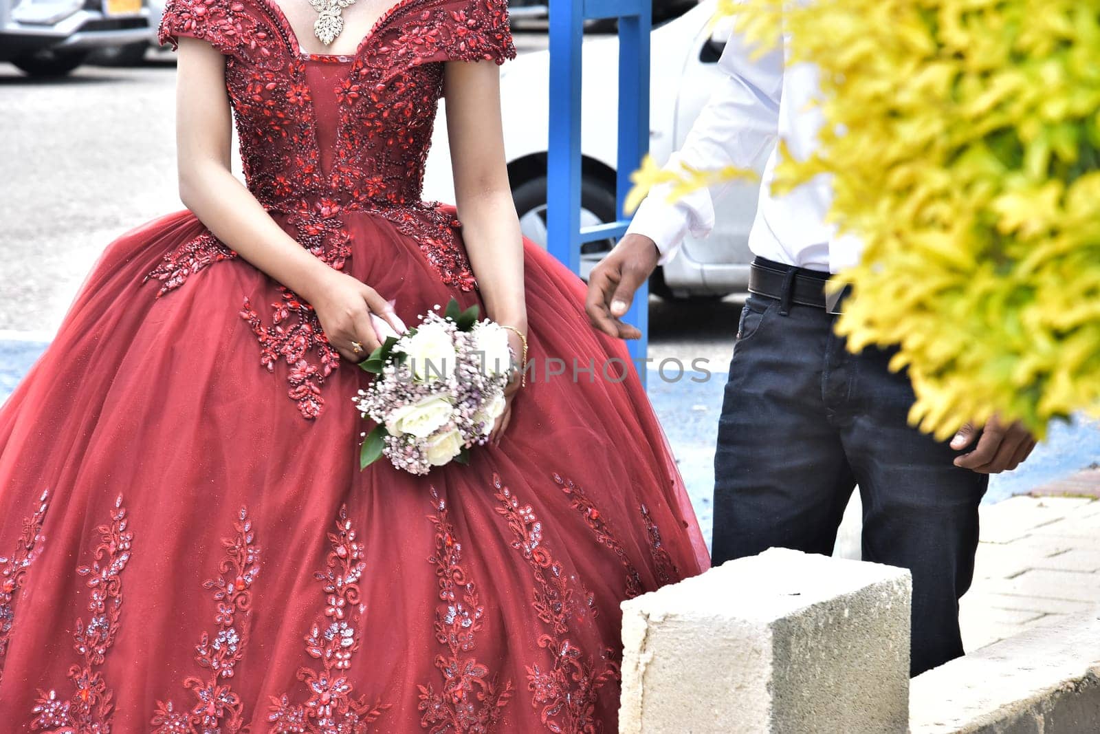 Newlyweds on the street, the bride in a scarlet dress, the groom in a white shirt, no faces. High quality photo