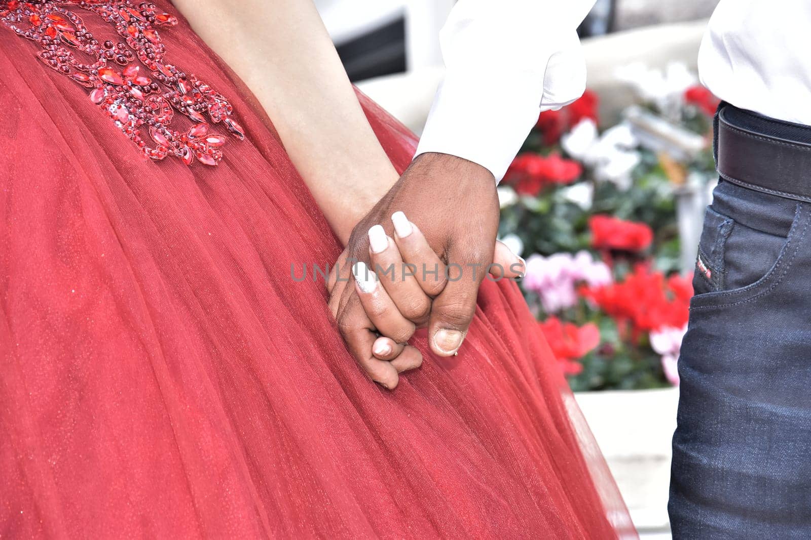 Newlyweds hold hands, the bride in a scarlet dress, the groom in a white shirt. High quality photo