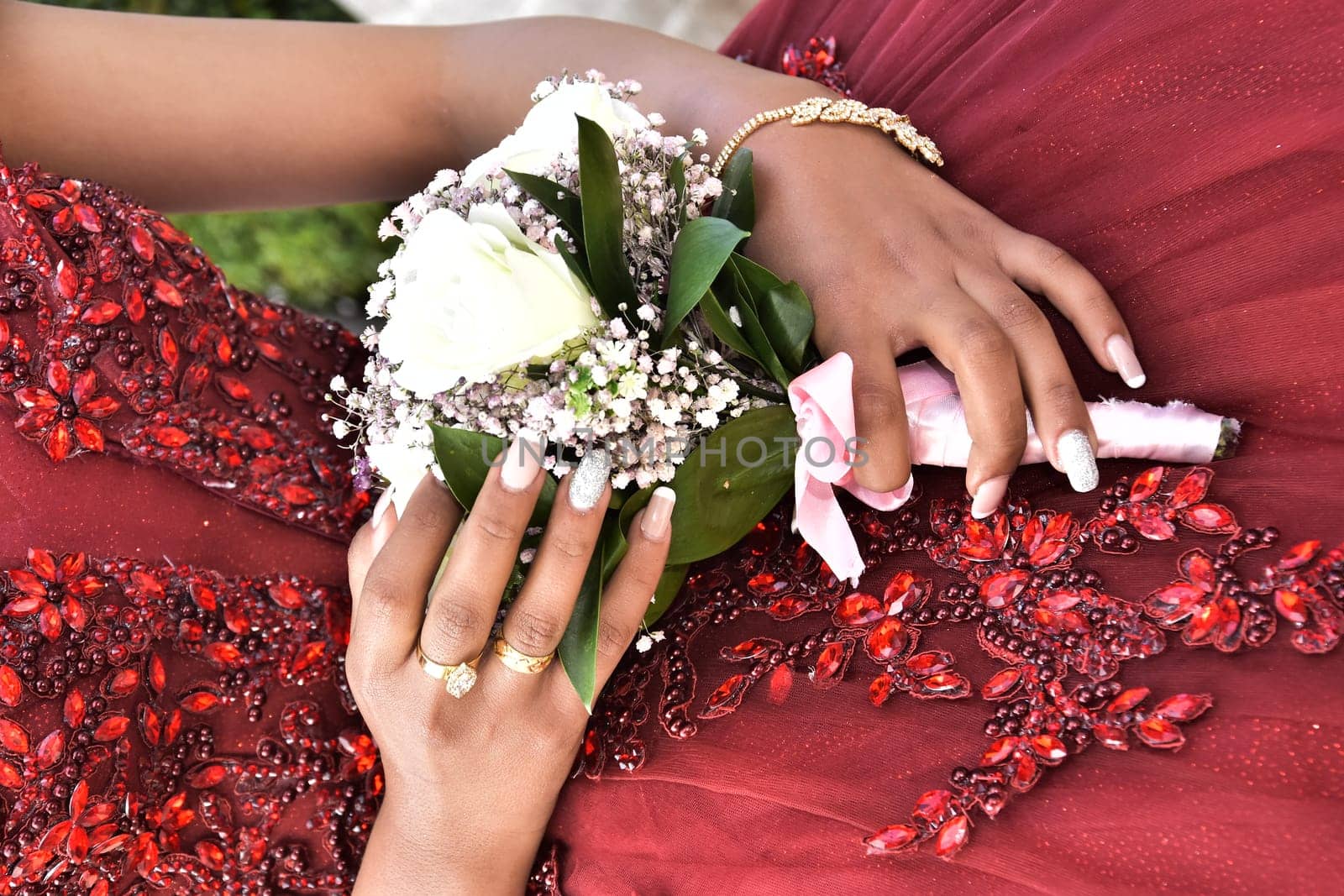 Hand of the bride girl with a wedding bouquet of white and pink flowers on a red dress. High quality photo