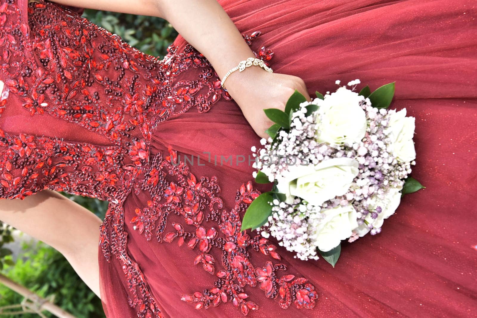 Hand of the bride girl with a wedding bouquet of white and pink flowers on a red dress. High quality photo
