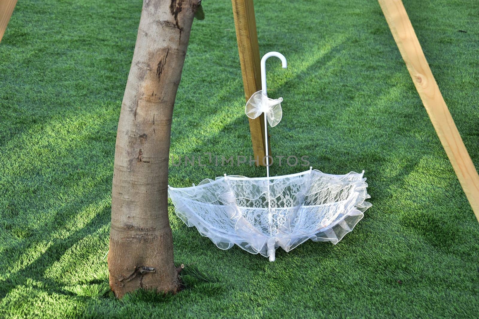 White lace wedding umbrella with yellow flowers thrown on green grass. High quality photo