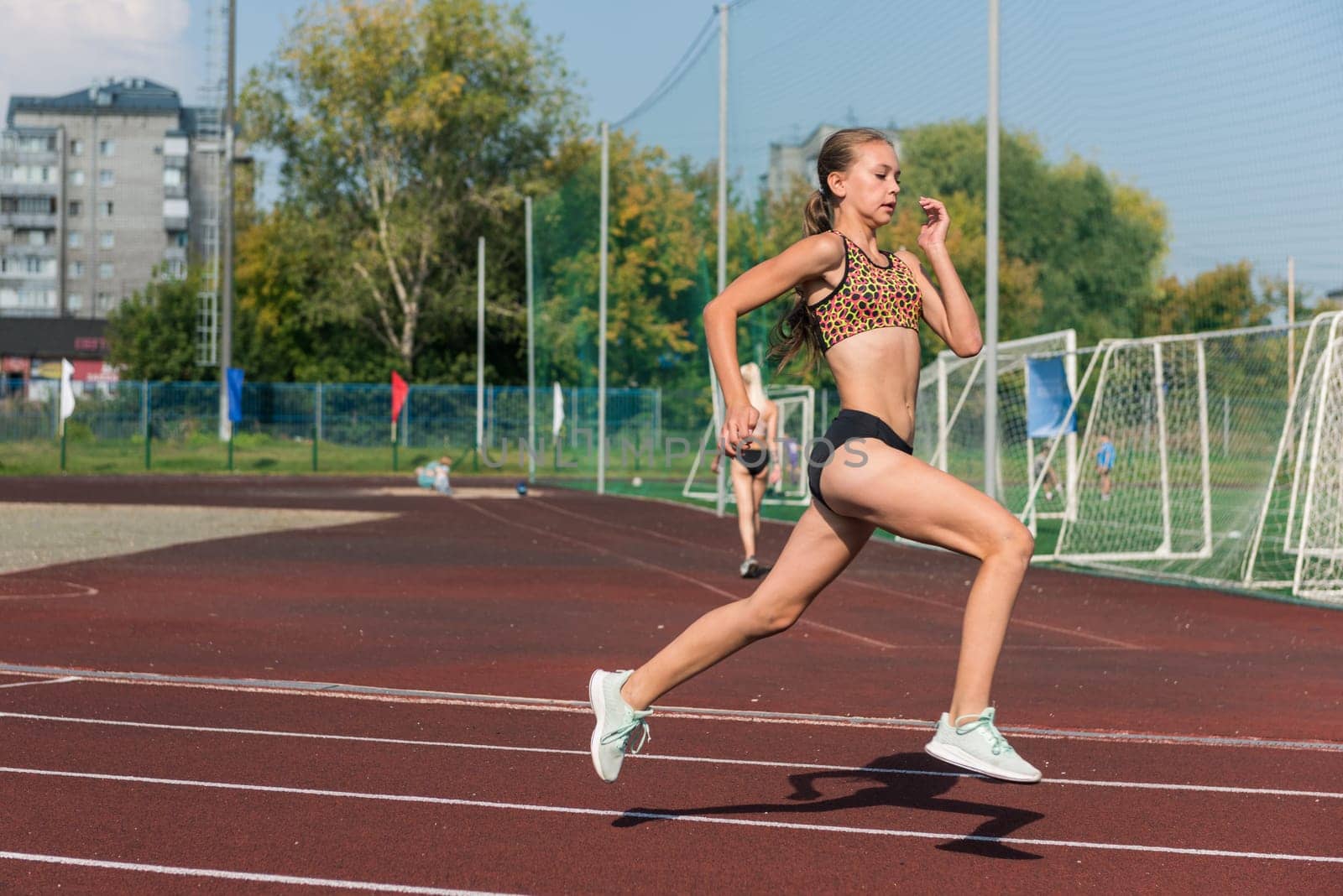 Young girl running on the running track at the stadium outdoors