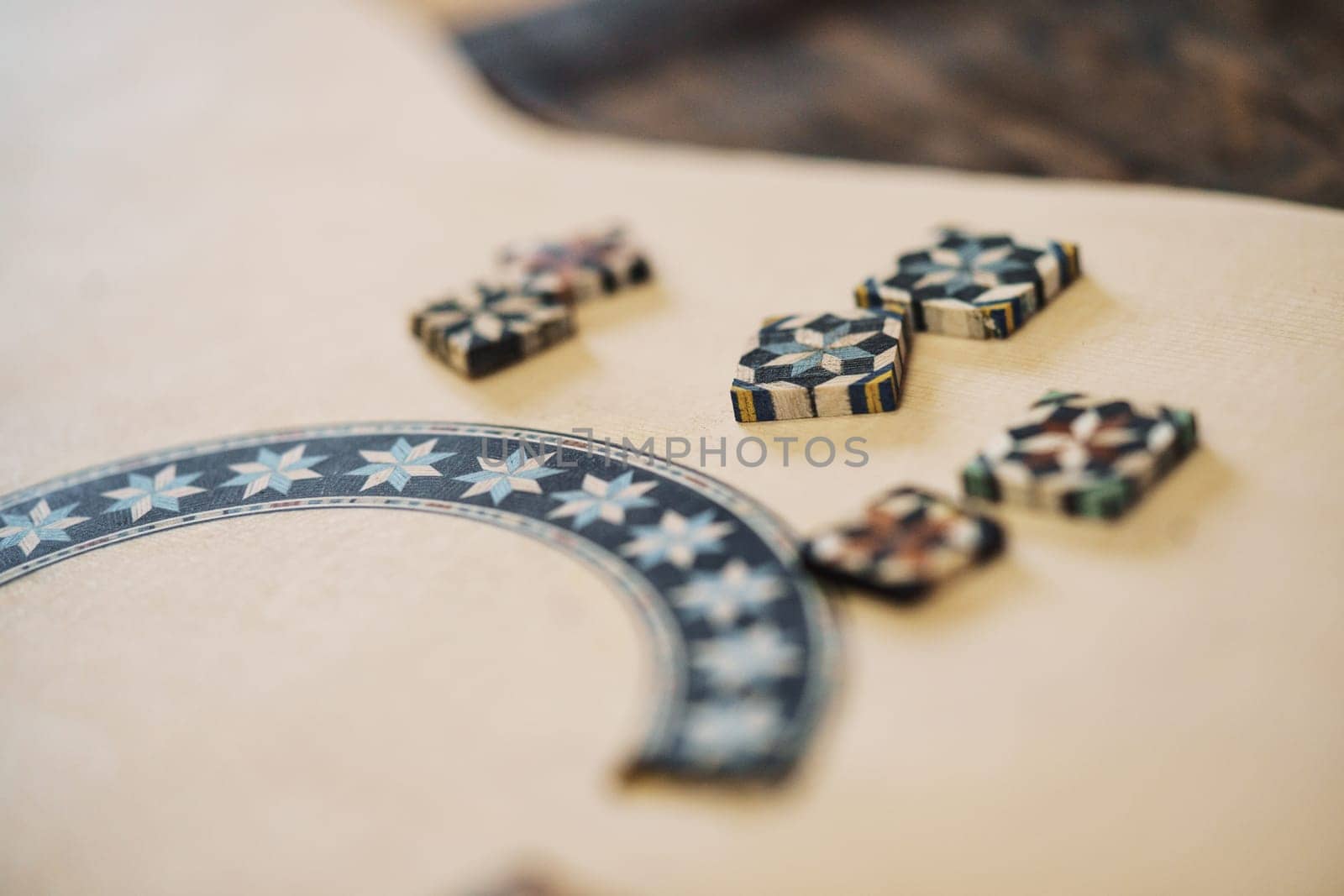 Closeup soft focus of wooden blocks with authentic ornaments of typical taracea of Granada, placed on Spanish flamenco guitar blank in luthier workshop