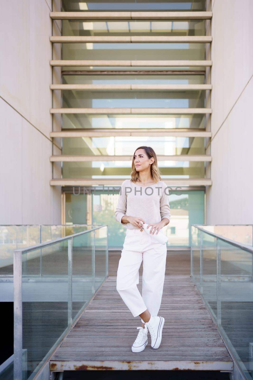 Middle aged woman near an office building carrying an eco-friendly ecological metal water bottle. by javiindy