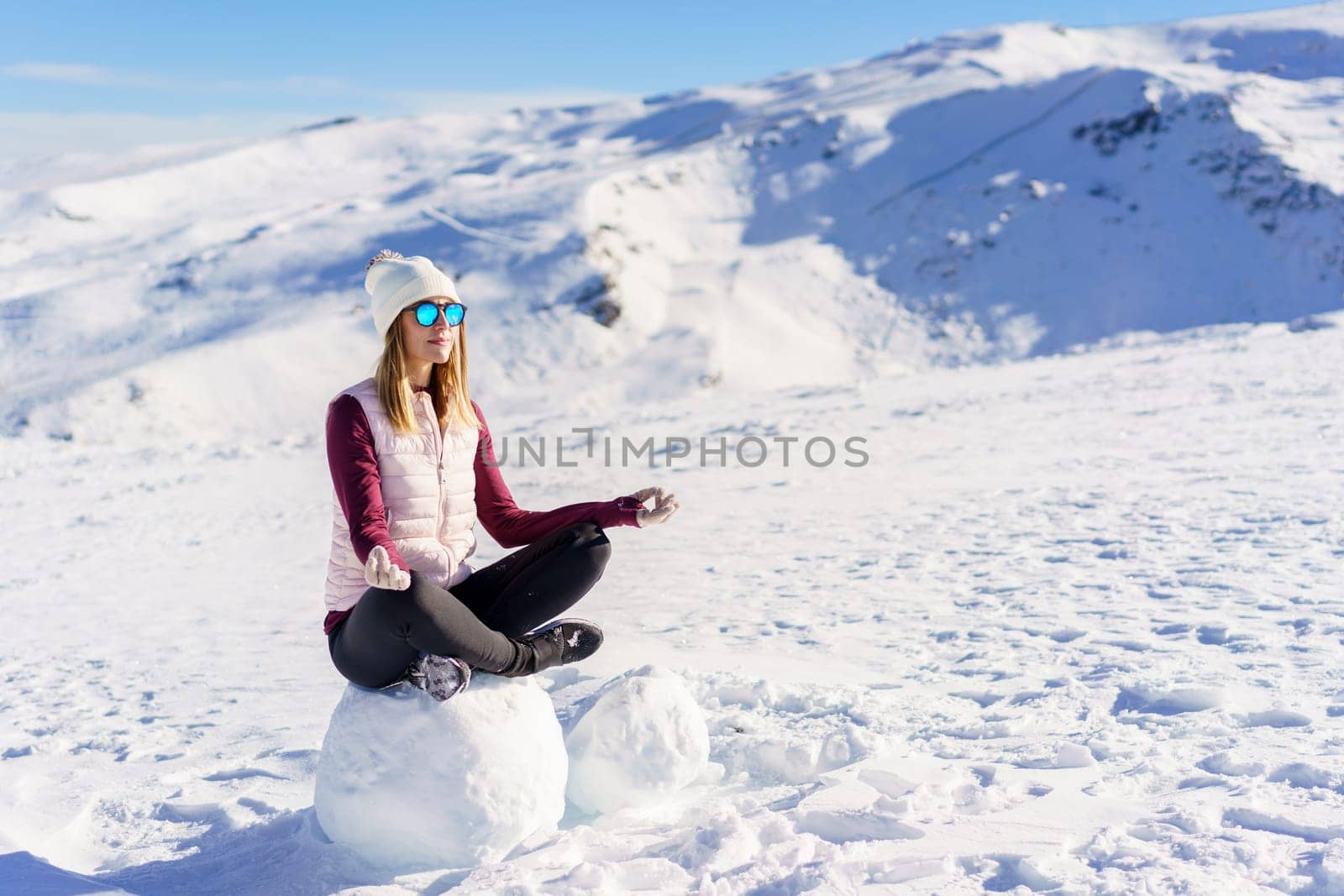 Cheerful woman sitting with lotus pose on snow by javiindy