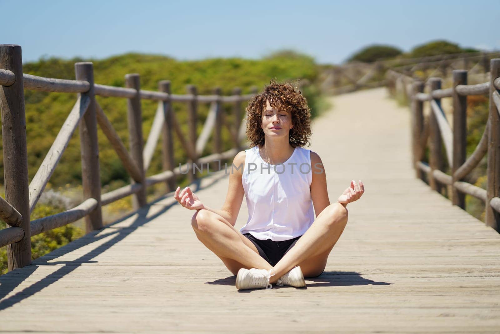 Young woman meditating on wooden pier by javiindy