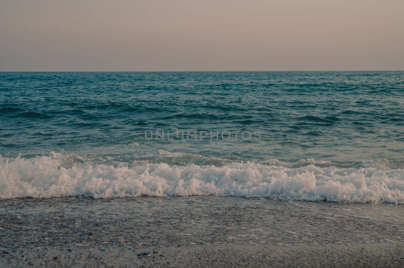 Waves of Mediterranean Sea rolling to the sandy Turkish beach. Beautiful Turkish evening.