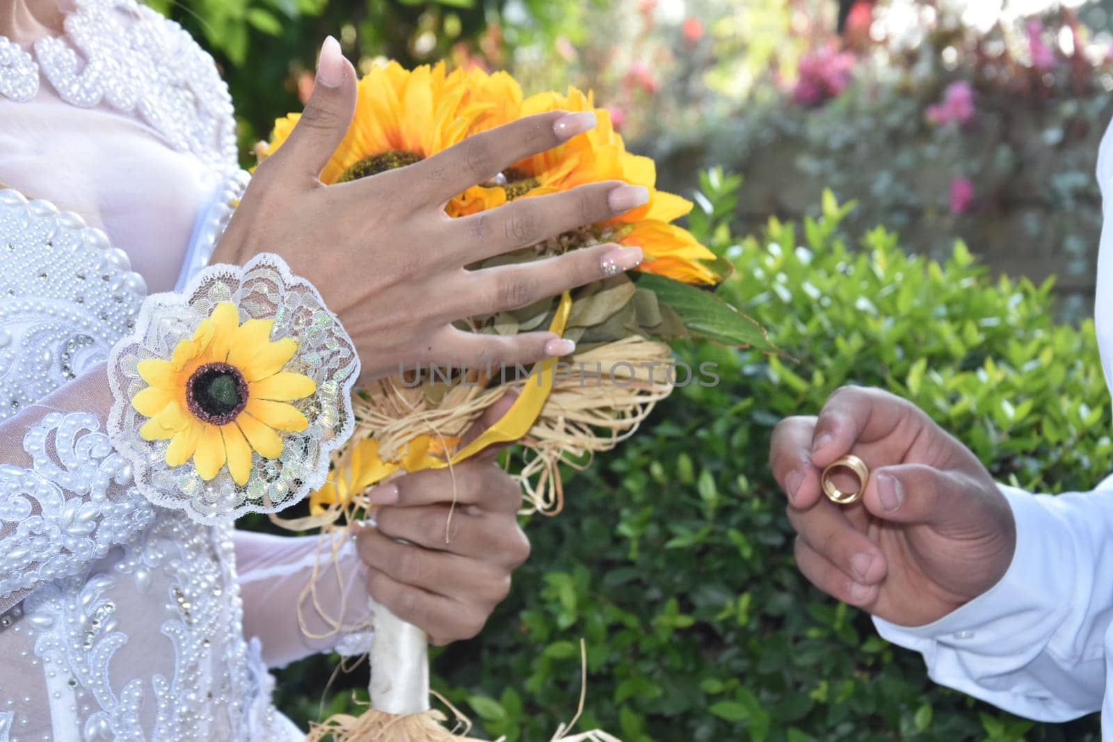 the groom's hands and nevsta with a bouquet of yellow flowers, a gold wedding ring. High quality photo