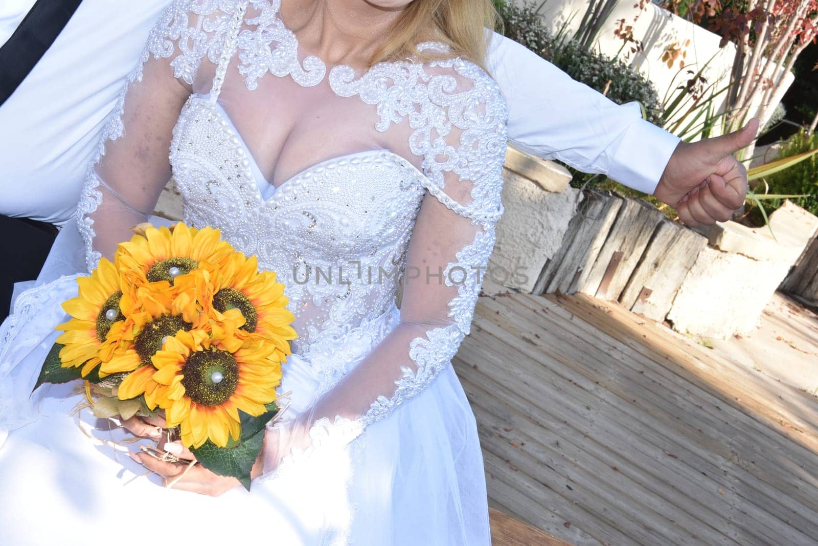 A bride in a white dress with lush breasts, a bouquet of yellow sunflowers,. No face. High quality photo