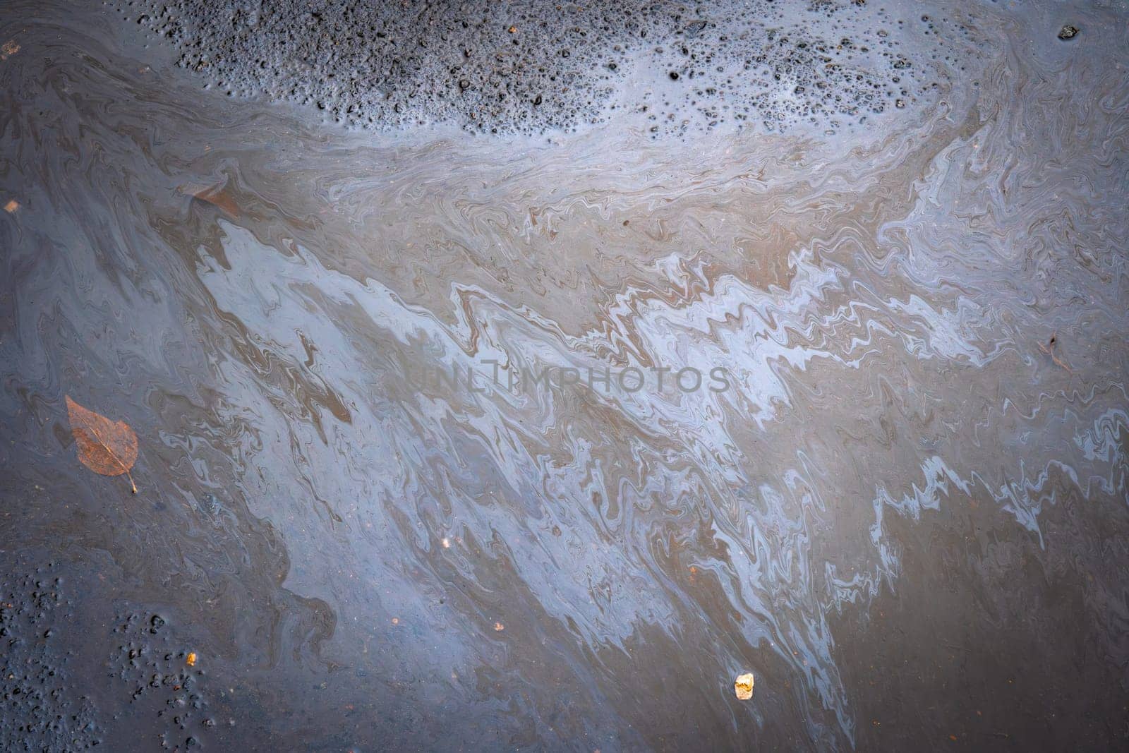 Dirty multi-colored stain from engine oil on asphalt. Environmental pollution concept.