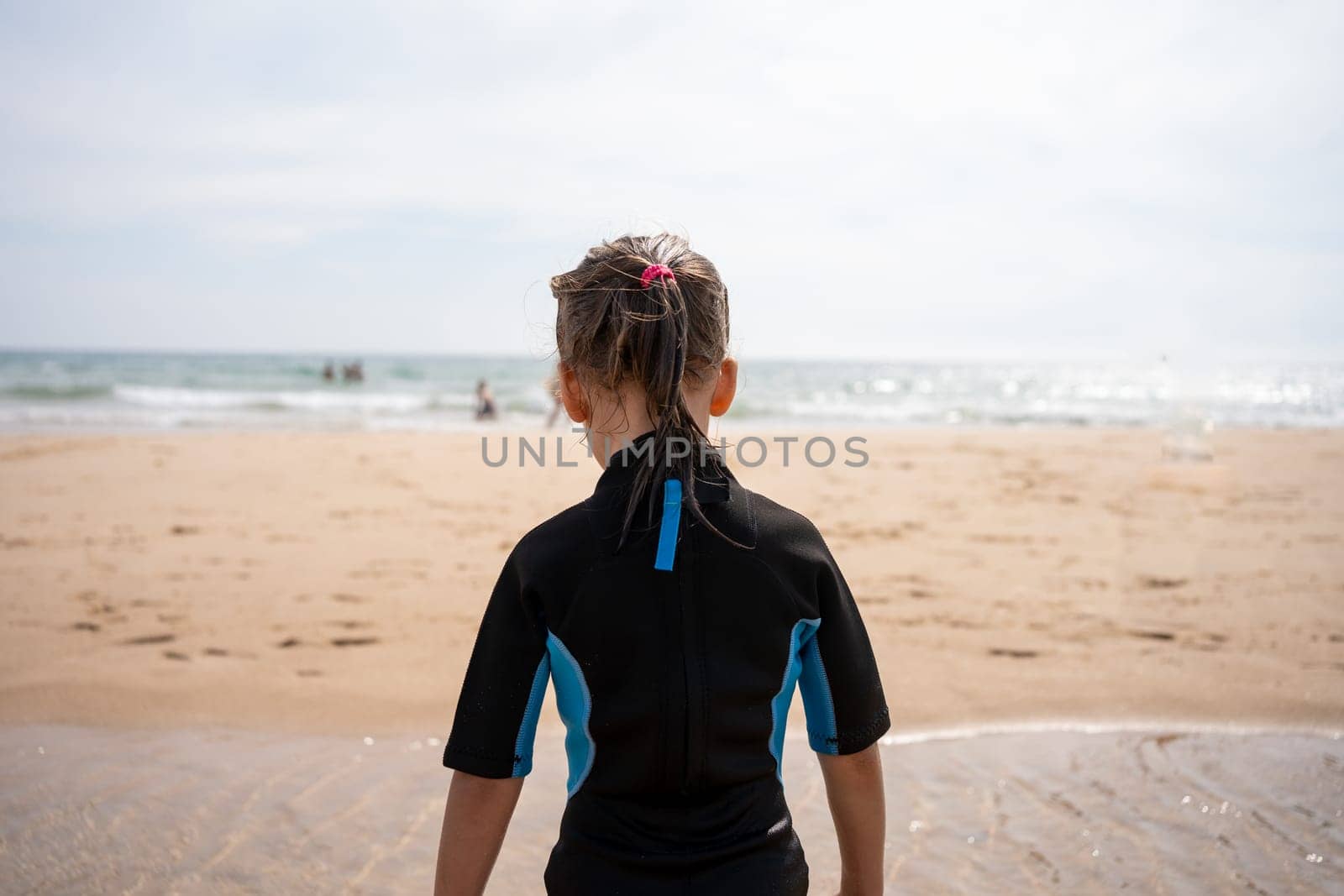 Little girl surfer in wetsuit standing ocean beach by andreonegin