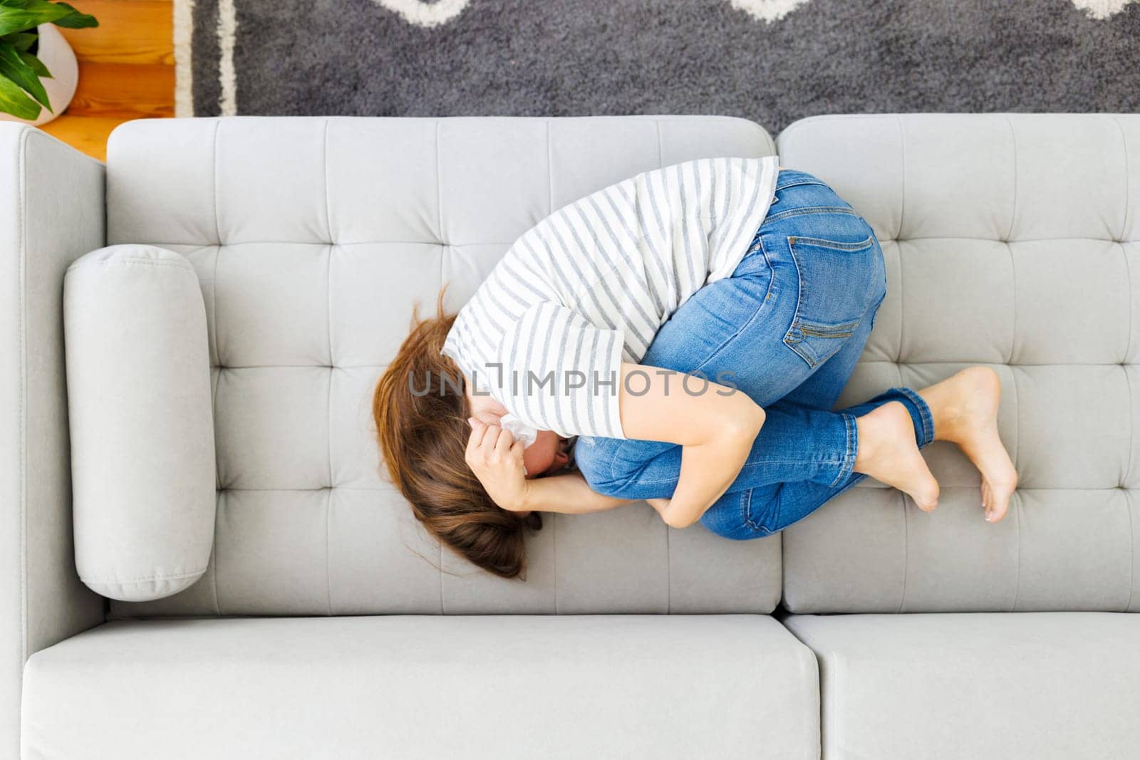 Frustrated woman covering face and crying, lying on sofa at home alone, upset female suffering from break up with boyfriend or divorce, bad relationship, feeling lonely and depressed.