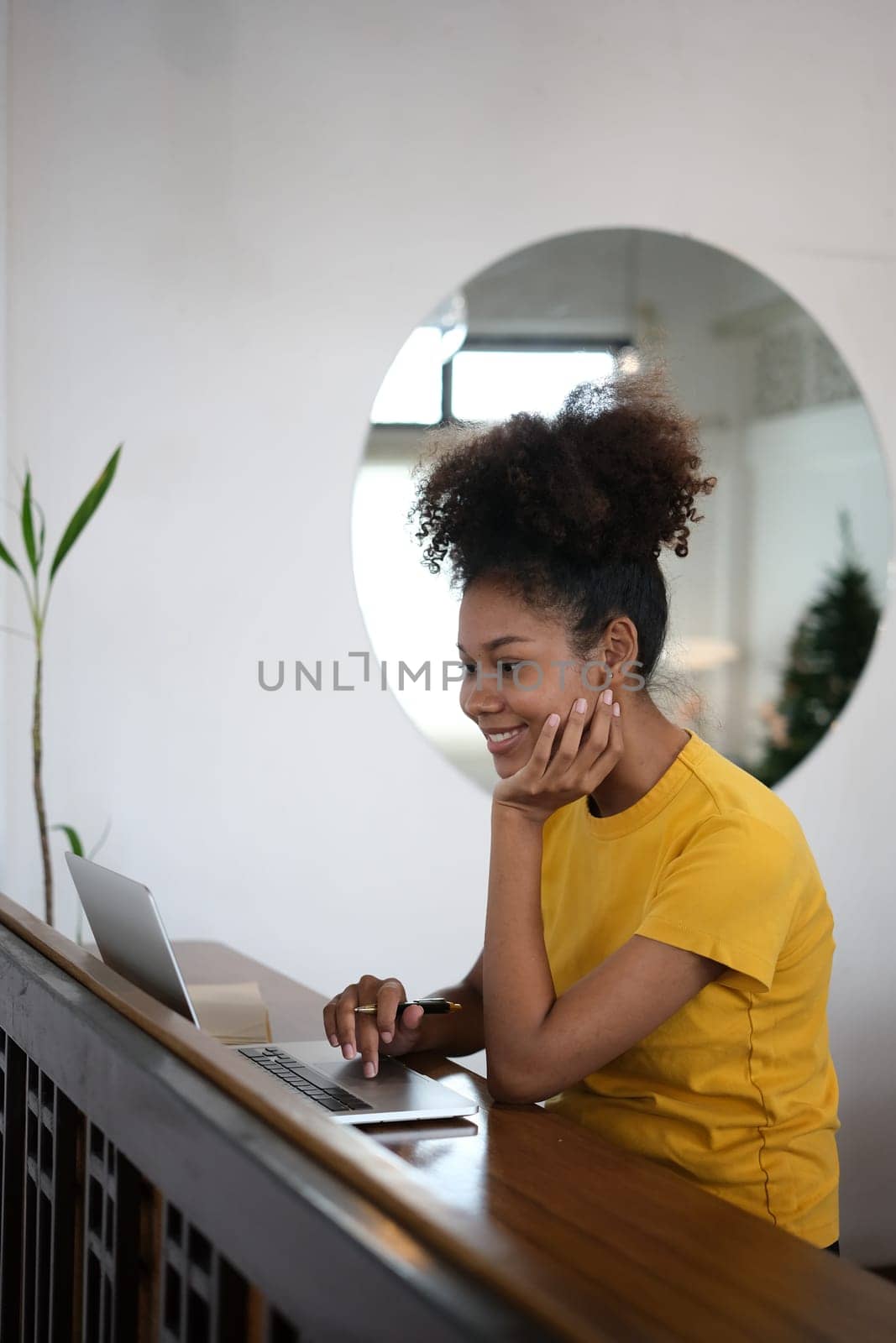 Cheerful African American university student looking at laptop screen, watching webinar, online course, doing homework.