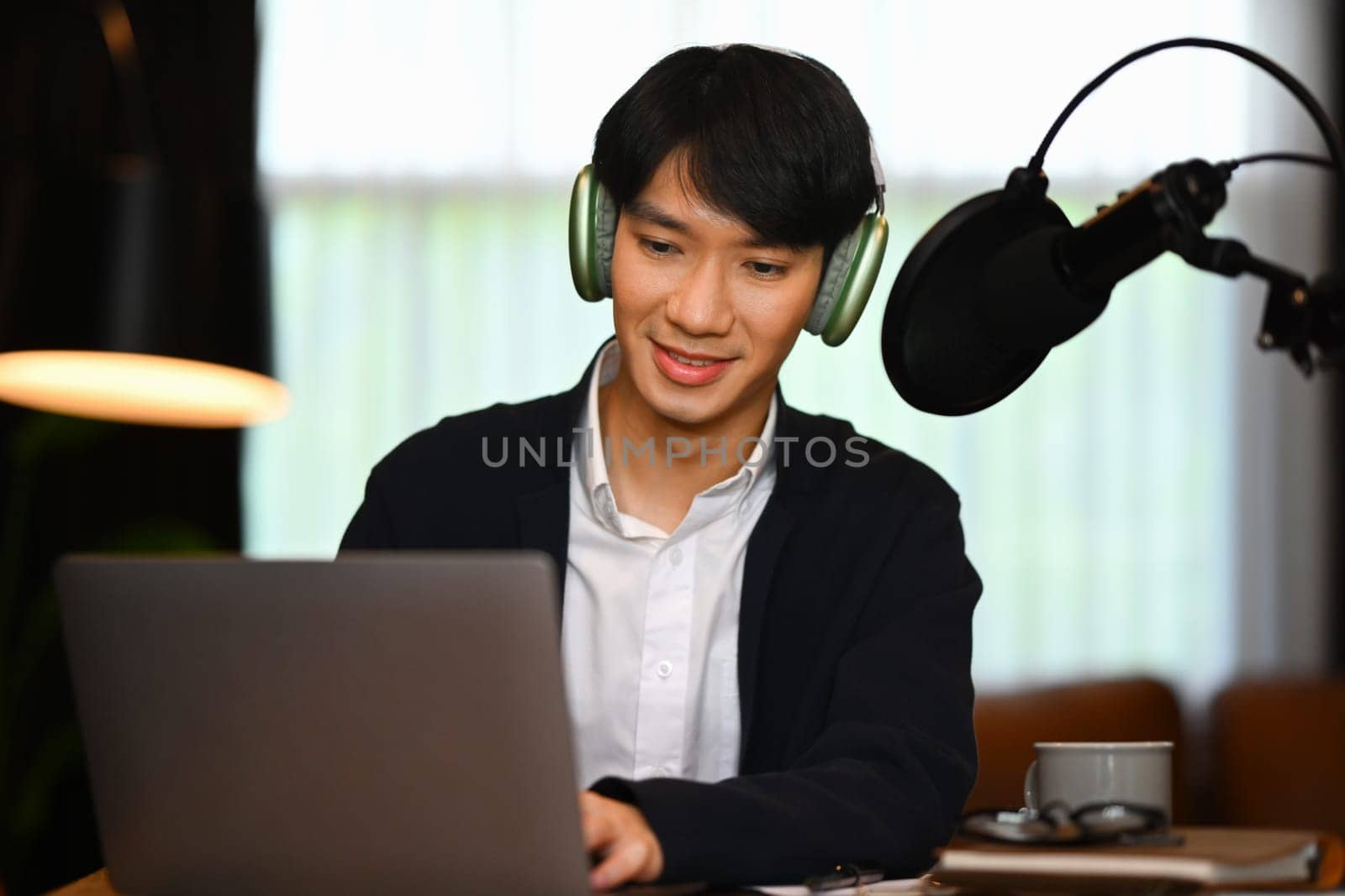 Man podcaster wearing headphone recording podcast from home studio. Radio, podcasts, blogging and technology concept.
