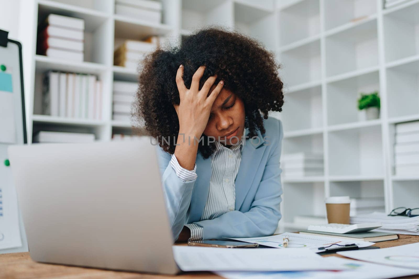 Burnout American African business woman in stress works with many paperwork document, migraine attack, Freelance, work at office.