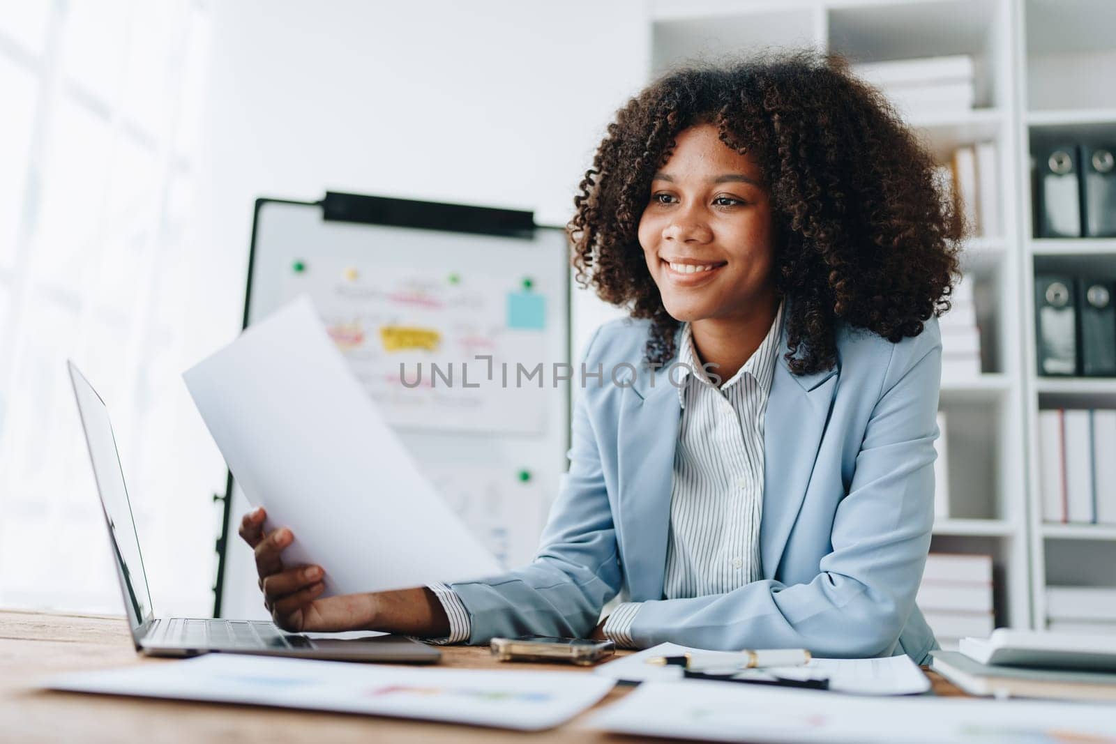 financial, Planning, Marketing and Accounting, portrait of african american employee checking financial statements using documents and calculators at work by Manastrong