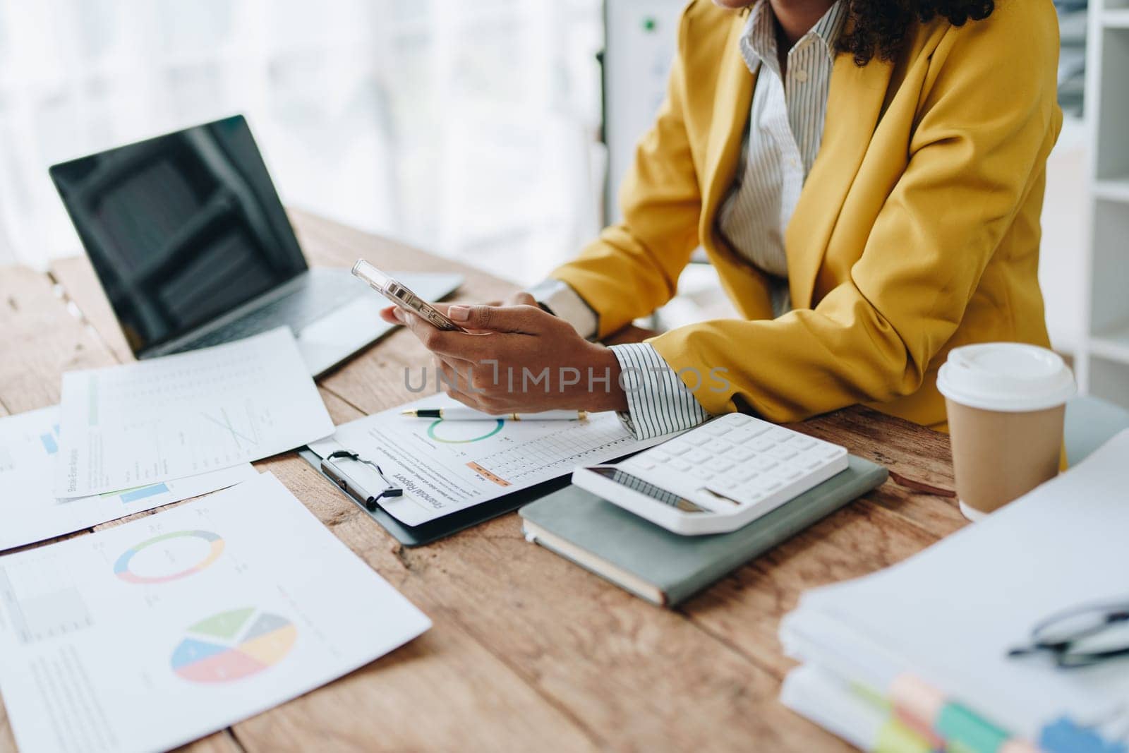 Woman American African using smart phone mobile and laptop computer with planning working on financial document, tax, exchange, accounting and Financial advisor.