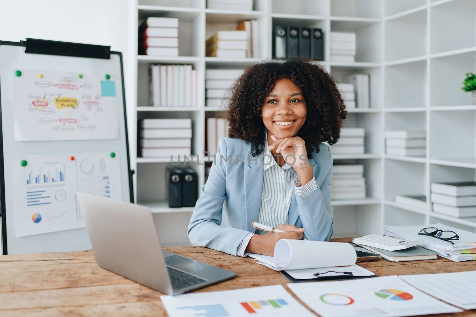 American African business woman using document, computer laptop, calculator, paperwork, documents, in winner and smiling Happy to be successful achievement success. finance and investment concepts by Manastrong