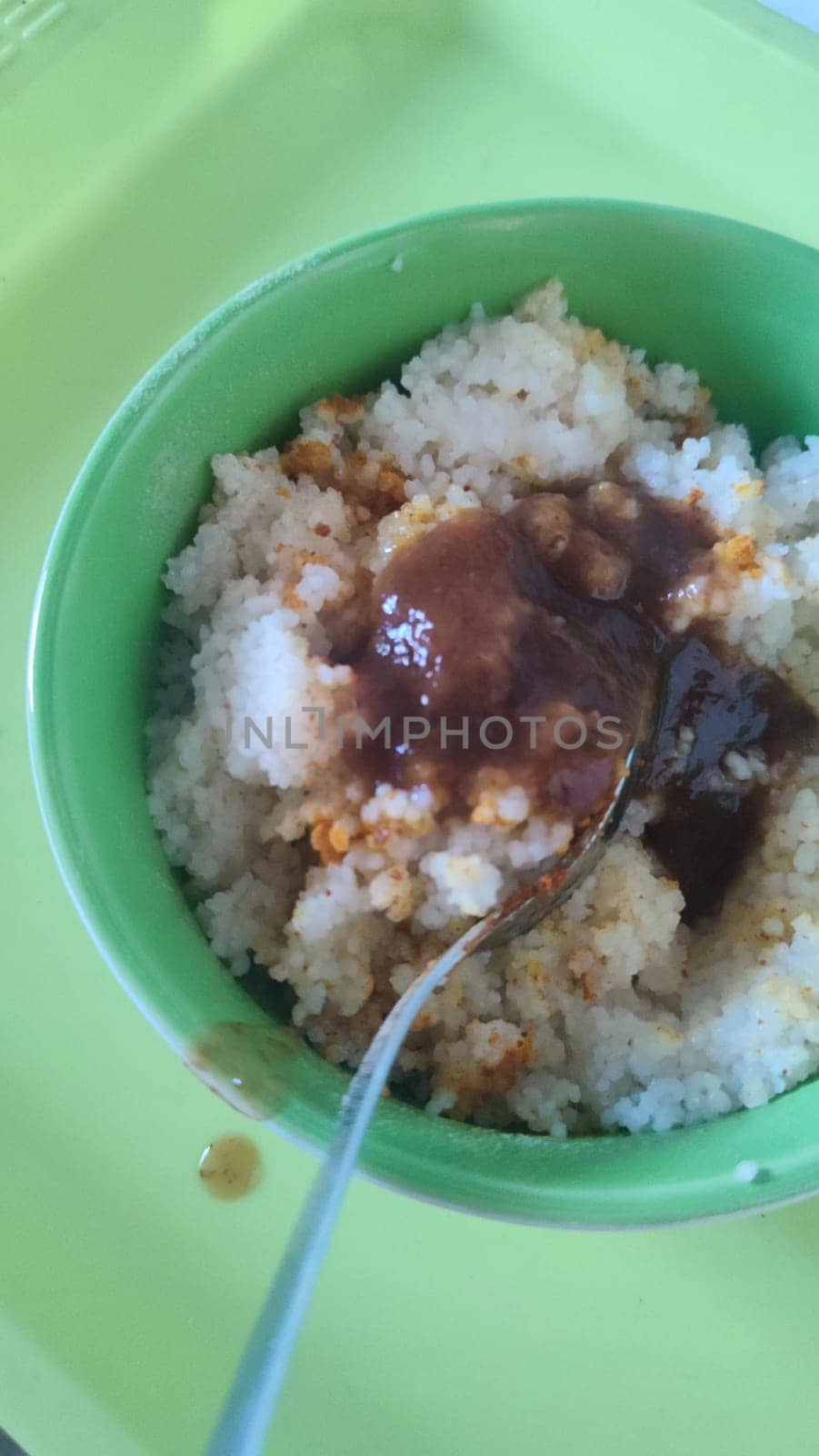 boiled couscous porridge in a green deep plate with a spoon, homemade food. High quality photo
