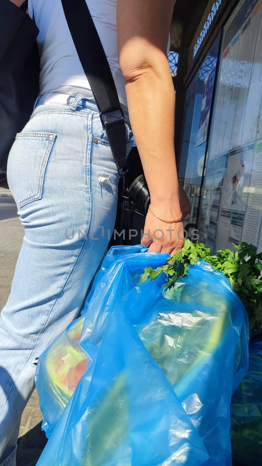 a young woman in jeans holds a bag of fresh celery leaves in her hand. High quality photo