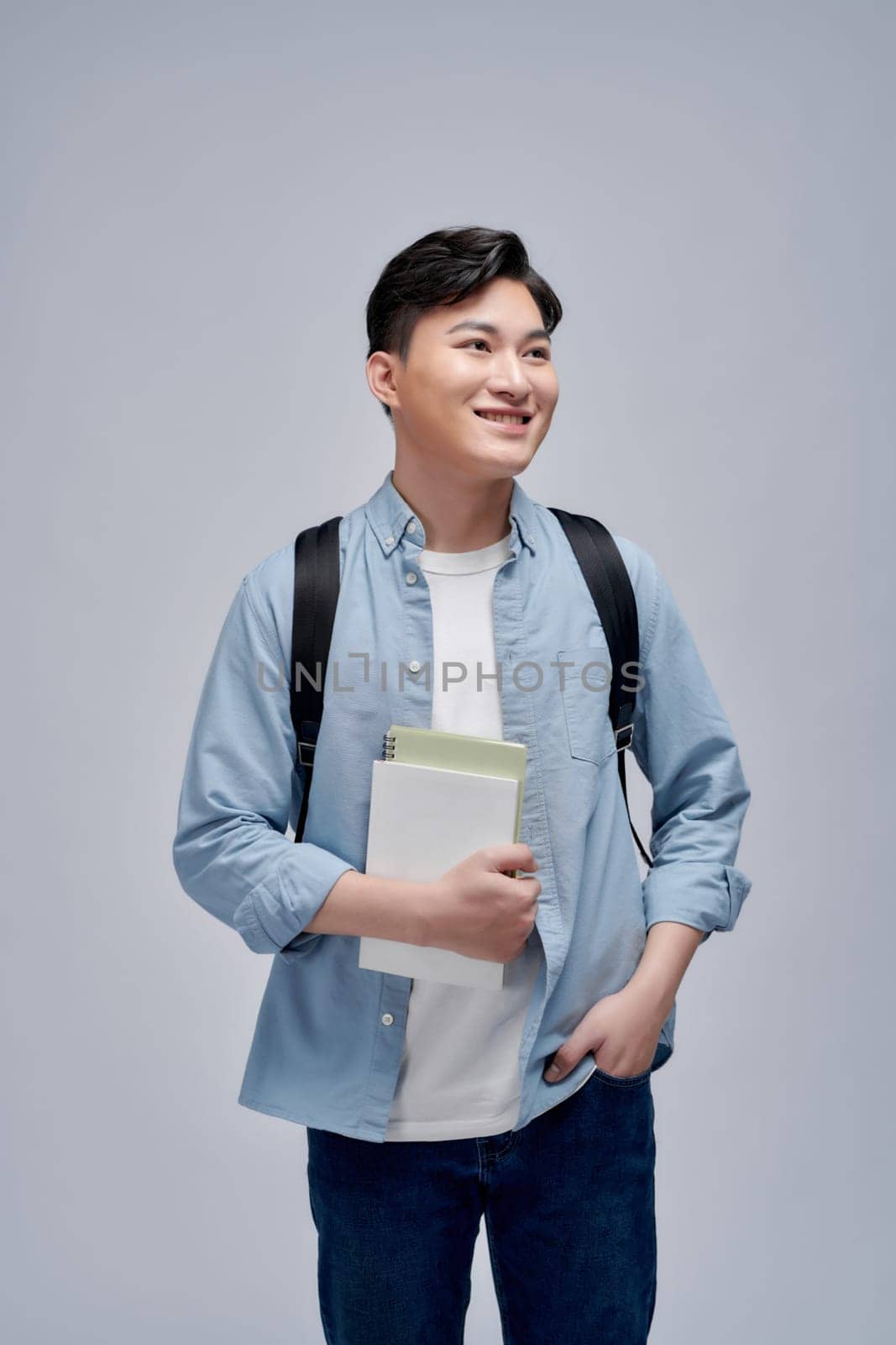 Full length portrait of a smiling young man dressed carrying backpack isolated, holding books, jumping