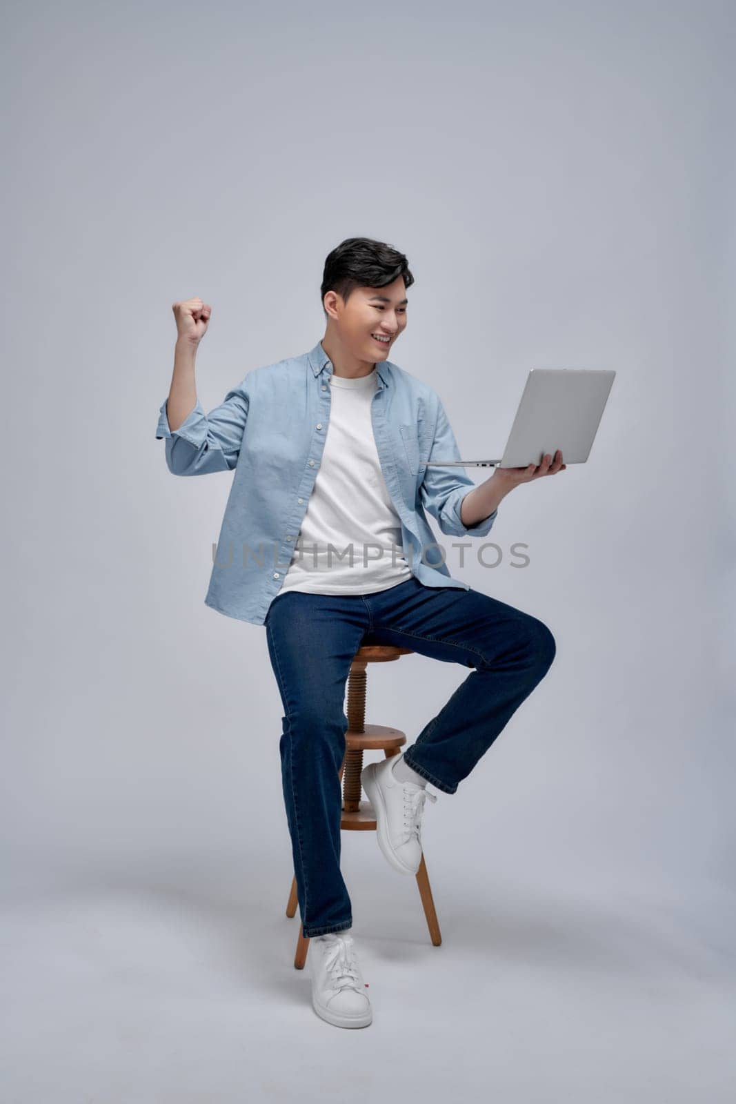 Young Asian business man sitting on chair and using laptop on background by makidotvn