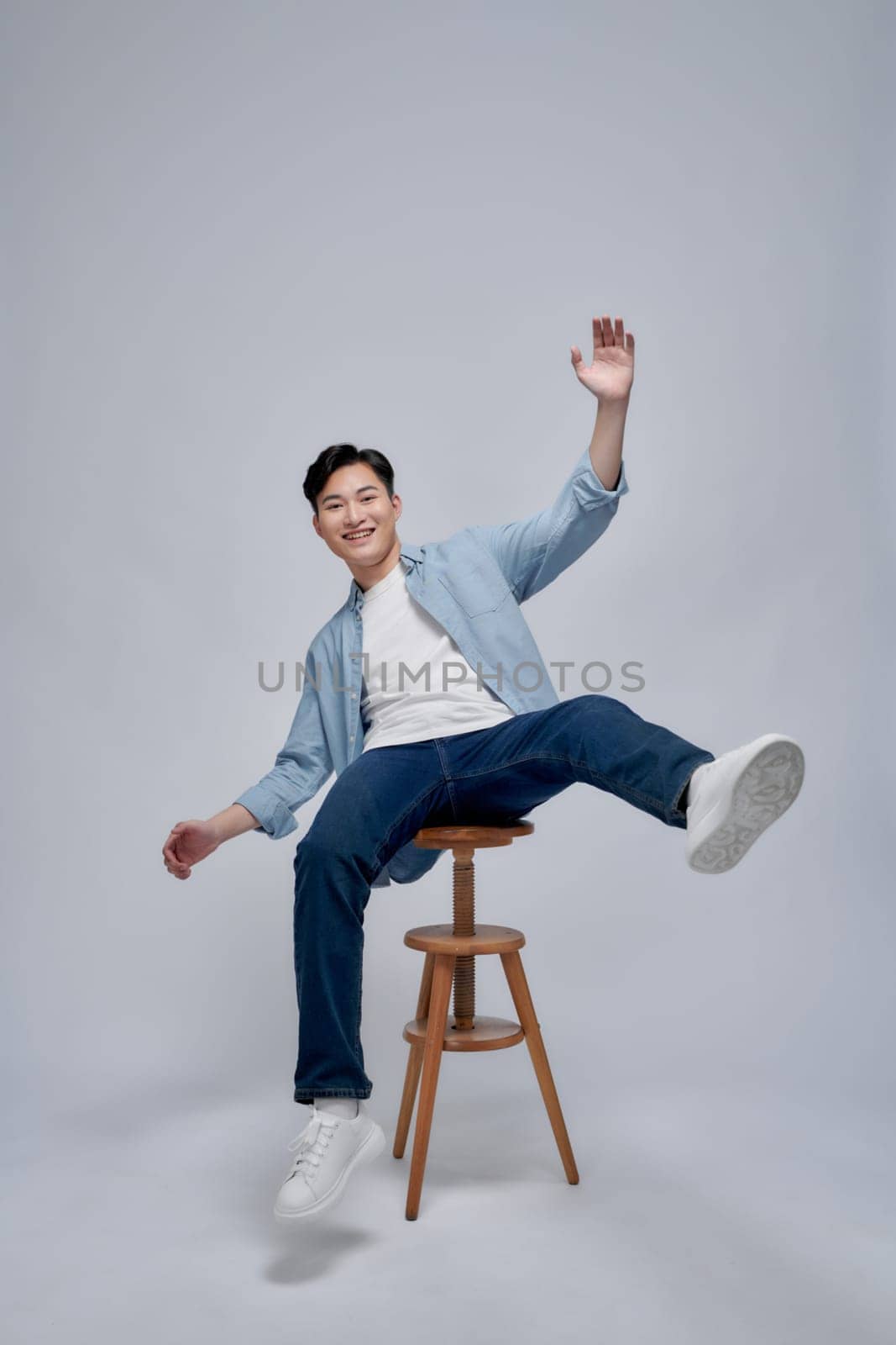 Photo portrait young man smiling sitting on wooden chair isolated on white background by makidotvn