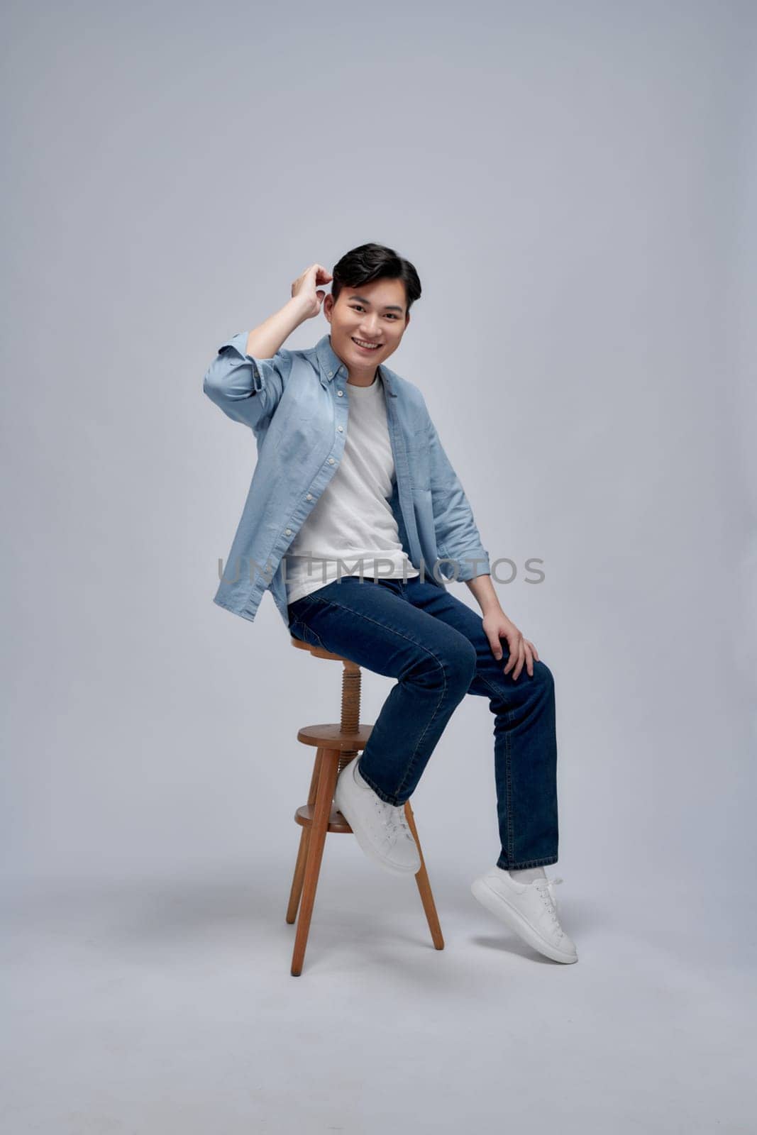 Feeling comfortable. Joyful positive young man sitting on a stool and smiling